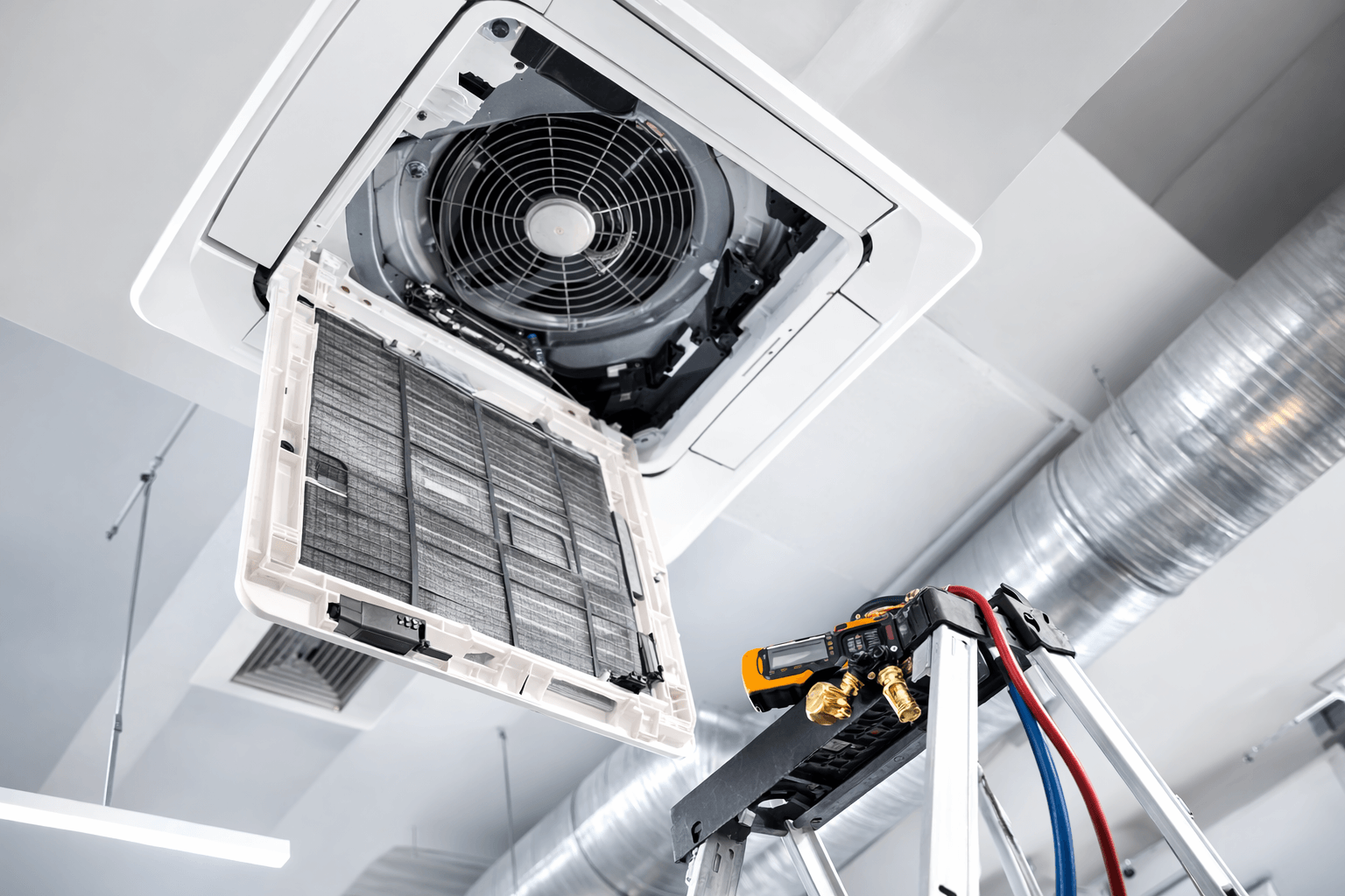 Wartung einer Klimaanlage im Gewerbebereich mit geöffnetem Deckengerät und sichtbaren Komponenten